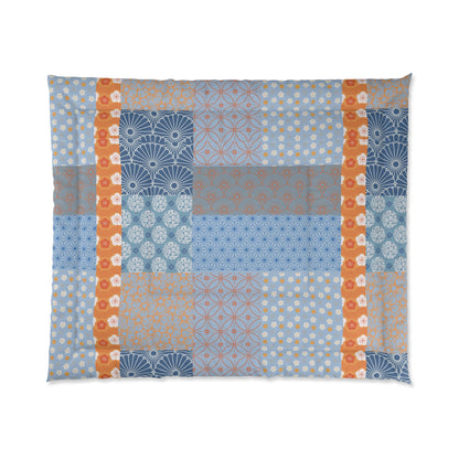 Patchwork quilt with geometric patterns in blue, orange, and brown on a white background. 