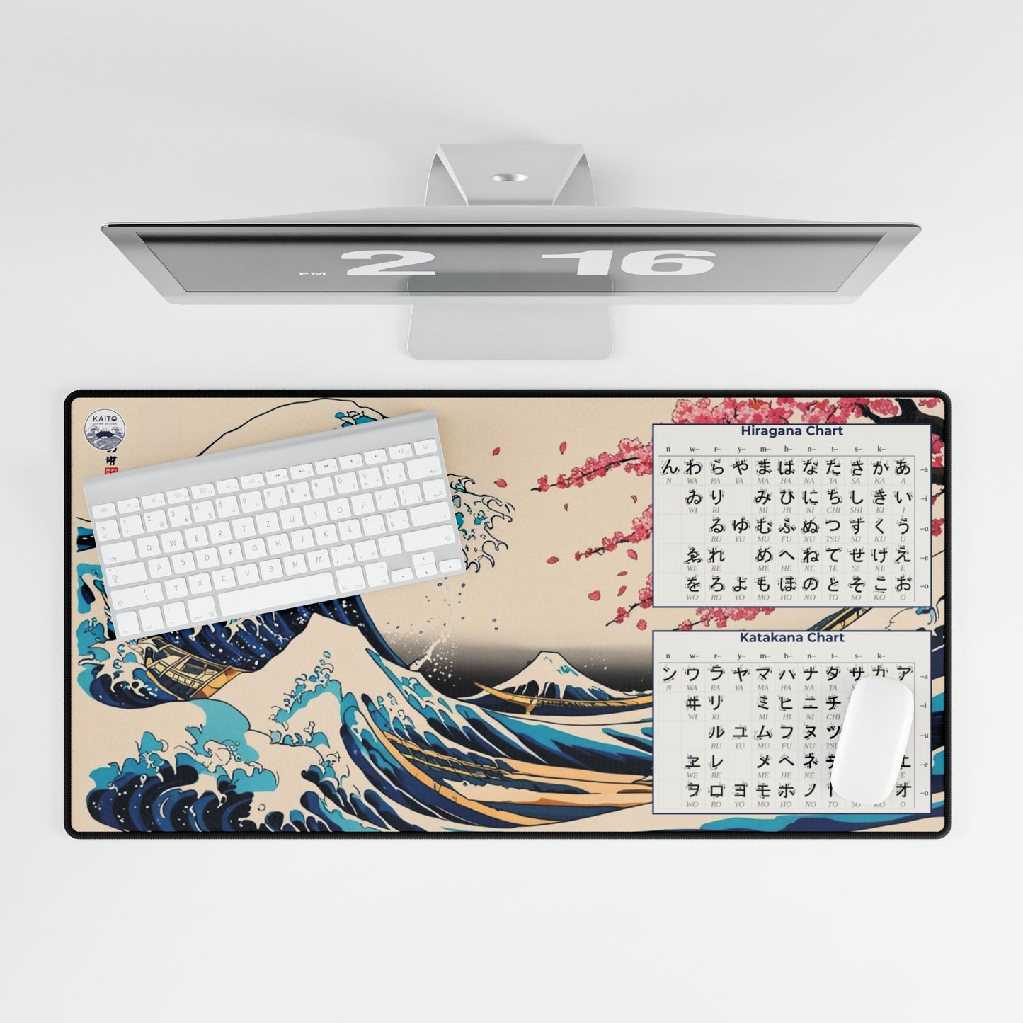 Desk setup with a large desk mat featuring a wave design and text, a keyboard, and a computer monitor.