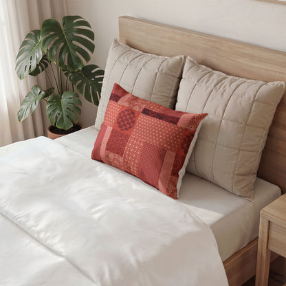 A styled bedroom scene showing a bed with white bedding, two large beige quilted pillows, and a smaller square decorative throw pillow in brown, mustard, and blue geometric patterns. A potted monstera plant sits beside the bed.