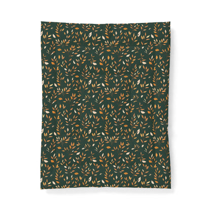 A rectangular fabric item, likely a blanket or throw, featuring an all-over repeating pattern of small leaves in warm tan, mustard, and cream on a dark forest green background.