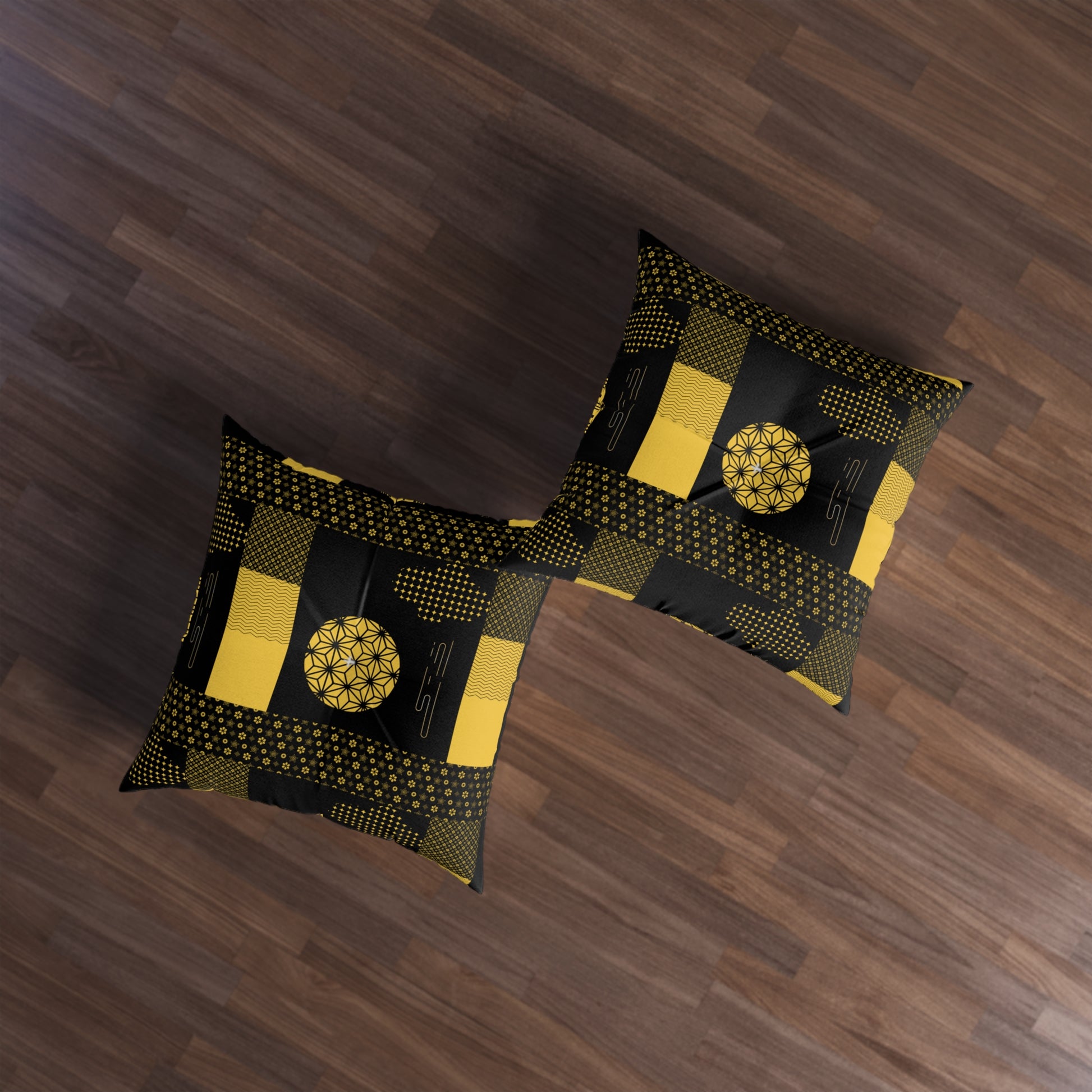 Two decorative throw pillows with a black and yellow geometric patchwork pattern, displayed on a dark brown wooden floor.