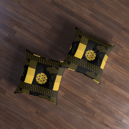 Two decorative throw pillows with a black and yellow geometric patchwork pattern, displayed on a dark brown wooden floor.