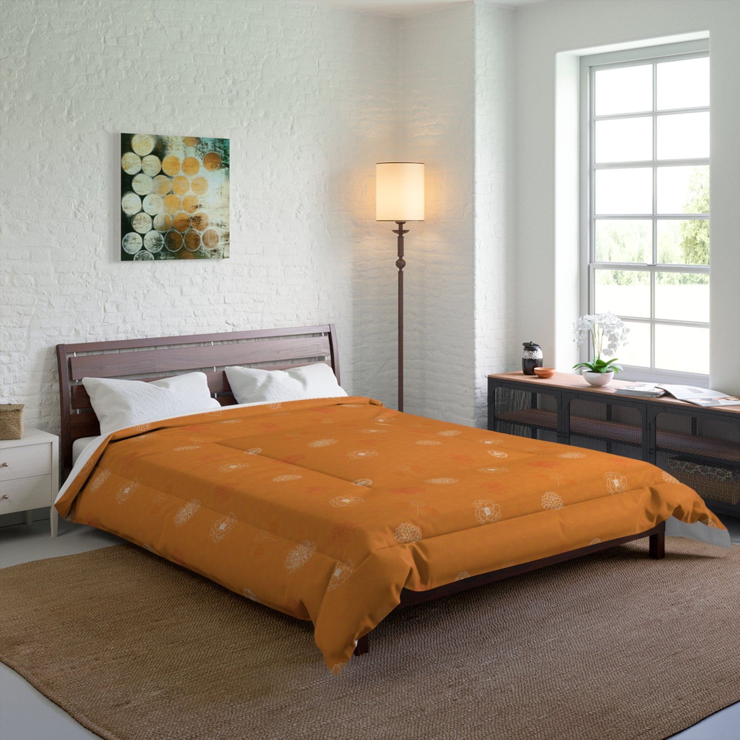 An orange patterned comforter set on a dark wood bed frame in a modern, bright bedroom with a white brick wall, floor lamp, and window.