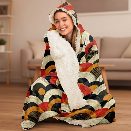 Person wrapped in a colorful hooded blanket with abstract patterns on a white background