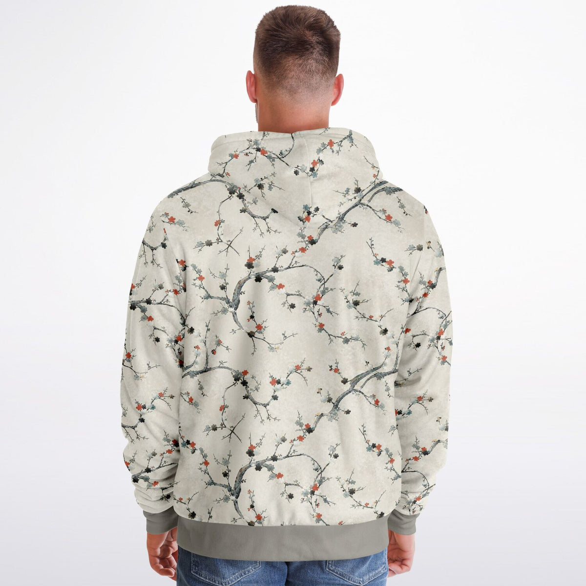 A man viewed from behind wearing a hooded sweatshirt with an all-over plum blossom branch print on a light beige background. The print features dark gray branches and small orange-red berries, with solid gray ribbed cuffs and hem.