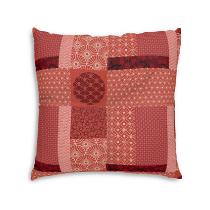 A square decorative throw pillow featuring a patchwork design of various red and pink Japanese-style patterns, including waves, dots, and geometric motifs, set against a plain white background.
