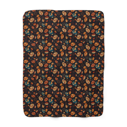 A rectangular throw blanket with rounded corners, featuring an all-over autumn pattern of acorns, leaves, and pinecones in orange, brown, and teal on a dark background, shown flat against a white background.