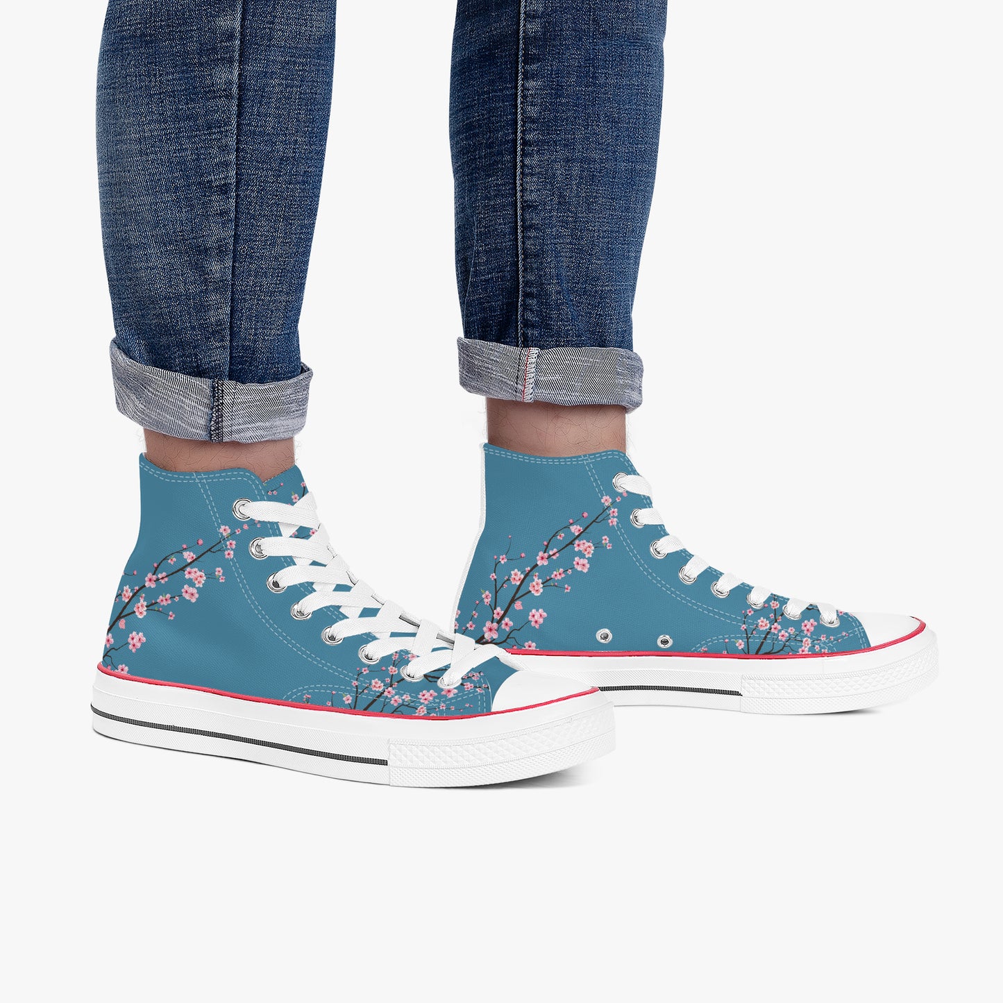 Blue high-top sneakers with floral design worn with rolled-up jeans on a white background