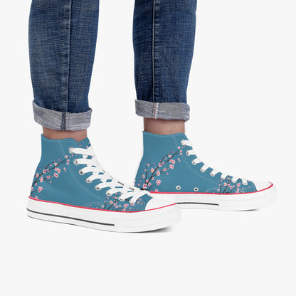 Blue high-top sneakers with floral design worn with rolled-up jeans on a white background