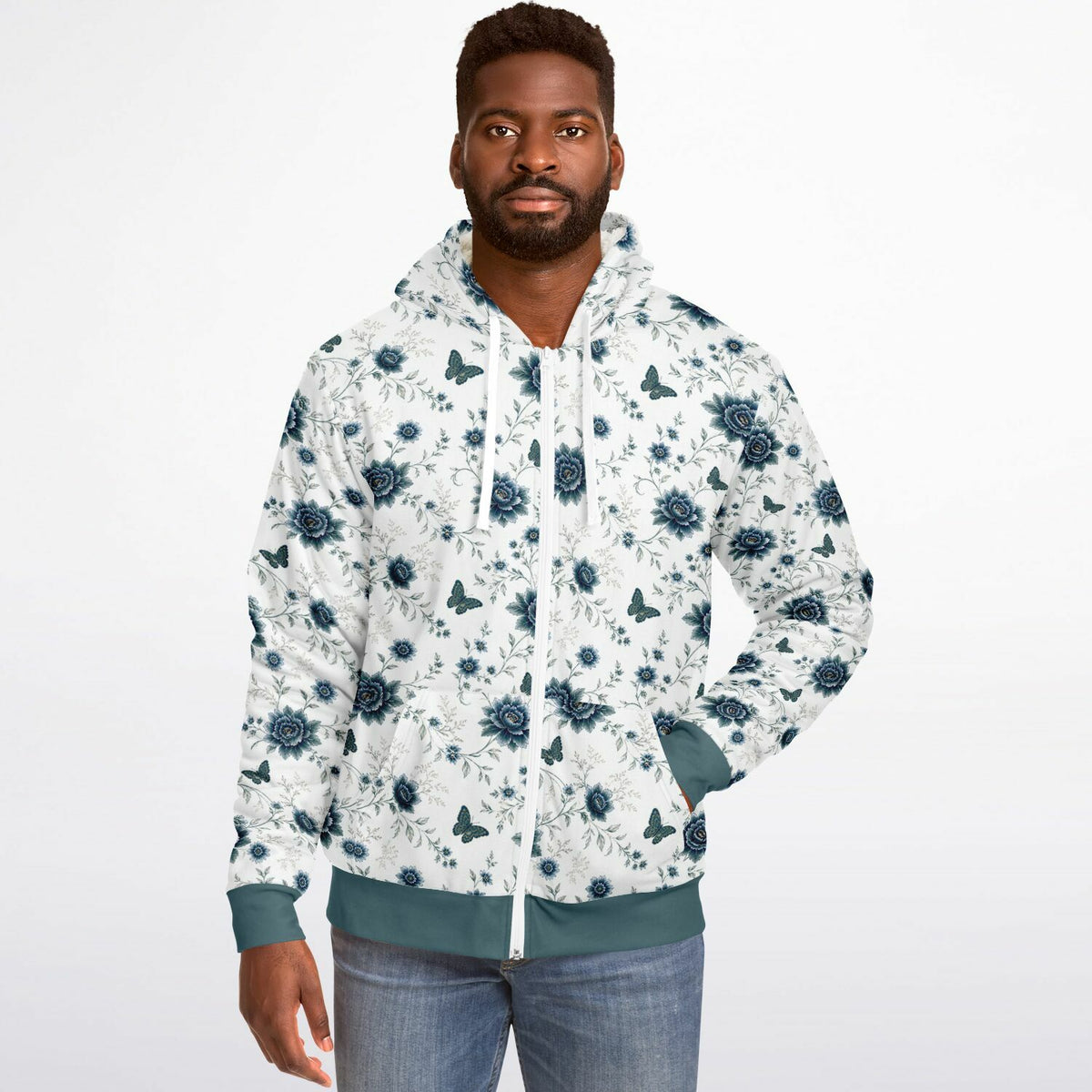 A man wearing a white zip-up hoodie with a blue floral and butterfly pattern, paired with blue jeans, against a plain white background.