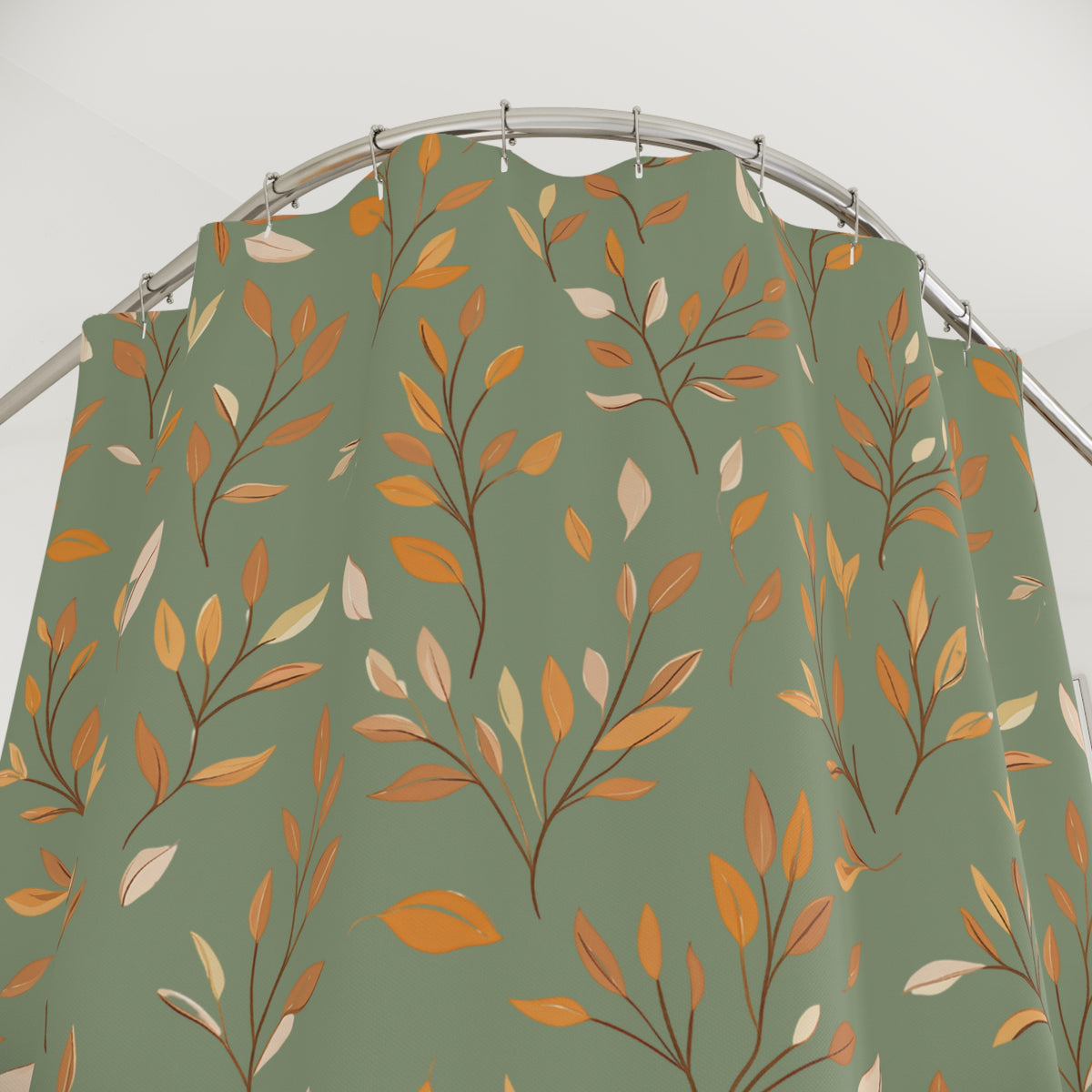 A sage green shower curtain featuring an all-over autumn leaf pattern in orange, mustard, and cream, hanging from a curved silver metal rod.