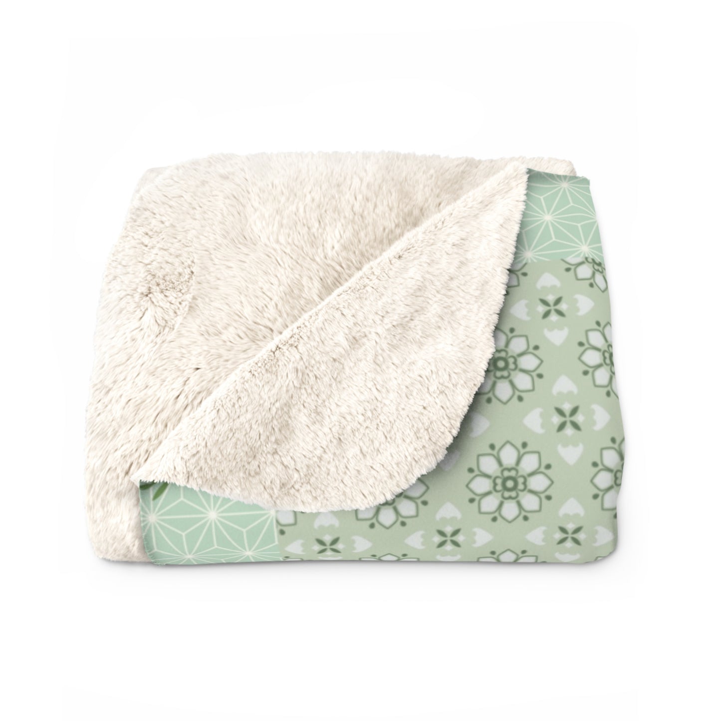 Folded blanket with white sherpa side and green patterned side on a white background