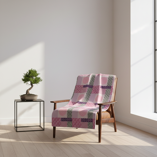 Wooden chair with a pink patchwork blanket in a bright room with a bonsai tree on a small table.