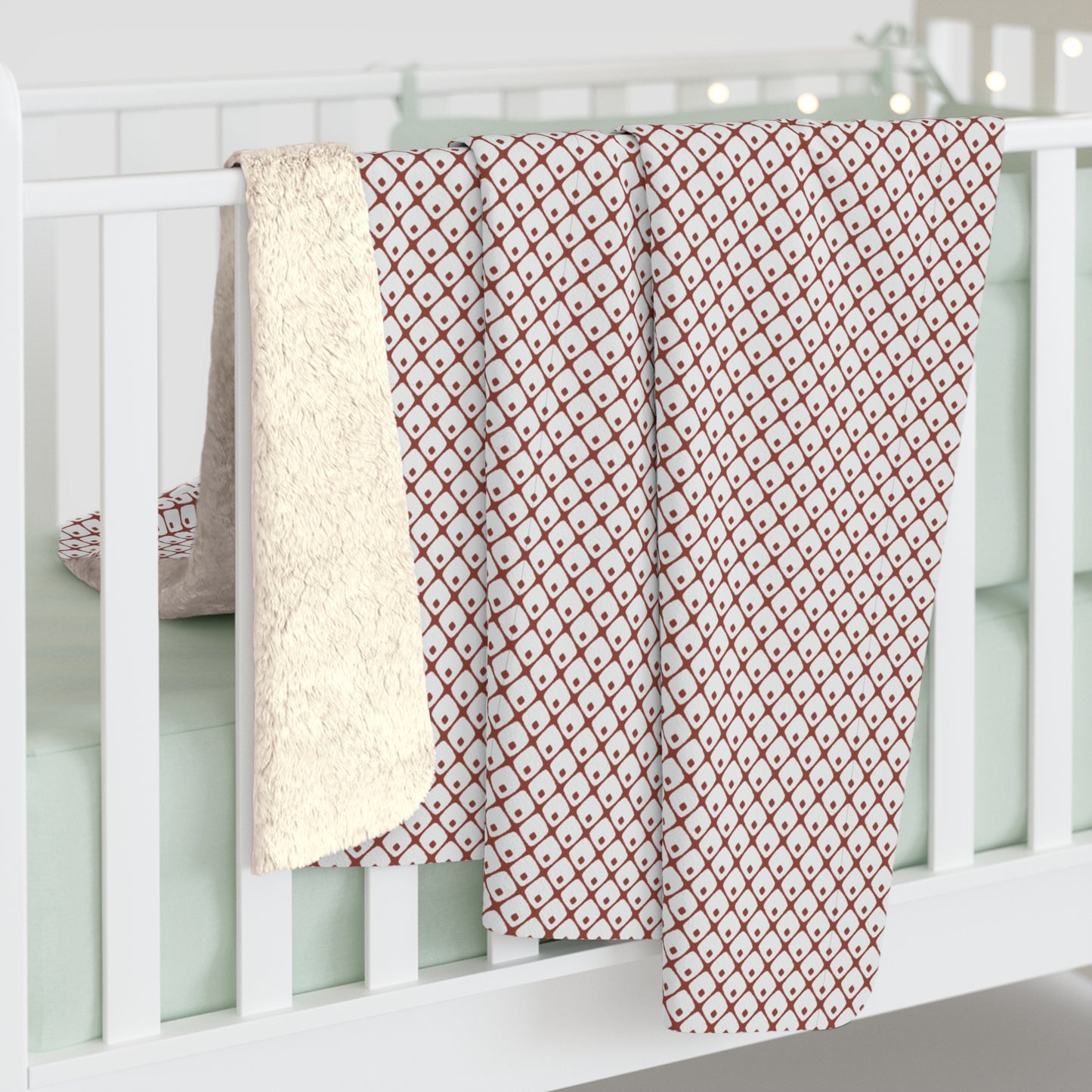 Red and white patterned blanket draped over a white crib