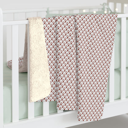 Red and white patterned blanket draped over a white crib