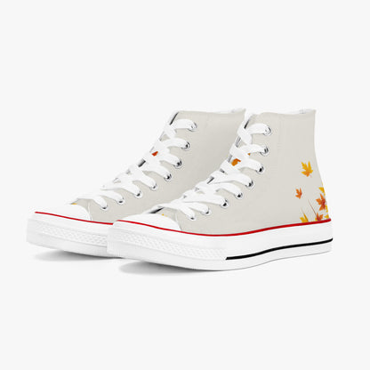 A pair of high-top canvas sneakers in off-white, featuring white laces, a red stripe along the toe, a black stripe along the midsole, and a small autumn leaf graphic in orange and yellow on the outer side.