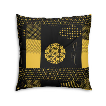 A square decorative throw pillow featuring a black and mustard yellow geometric patchwork design with floral and geometric patterns, shown against a plain white background.