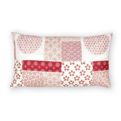 A rectangular lumbar pillow featuring a patchwork design of various red and pink Japanese patterns on an off-white background, set against a plain white studio backdrop.