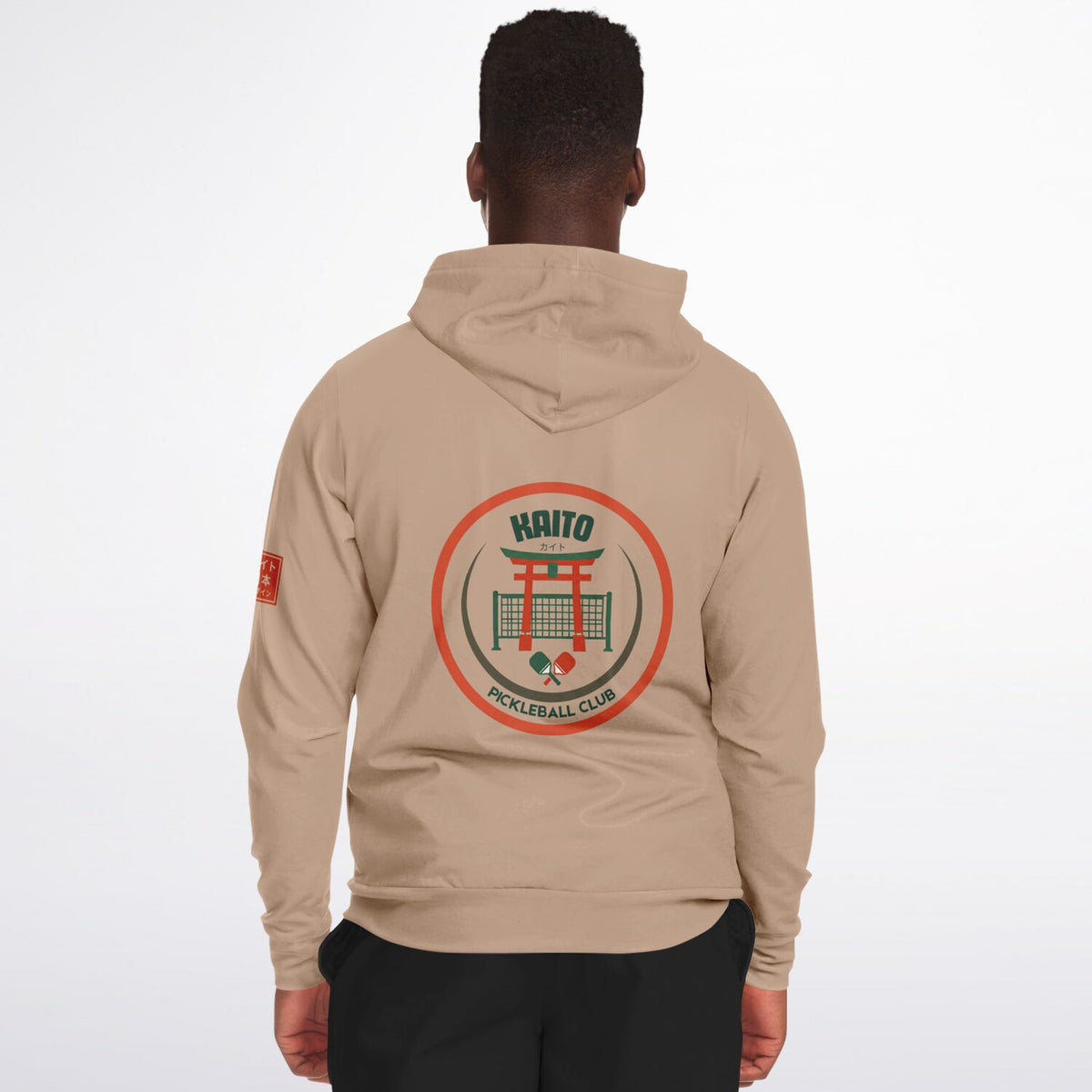 A man viewed from behind wearing a beige hoodie with a large circular 'Haito Pickleball Club' graphic on the back and a small red graphic on the left sleeve, set against a plain white background.