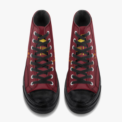 A pair of high-top sneakers shown from a top-down view, featuring a burgundy red leather upper, black laces, black rubber toe caps and soles, and small yellow accents on the sides.