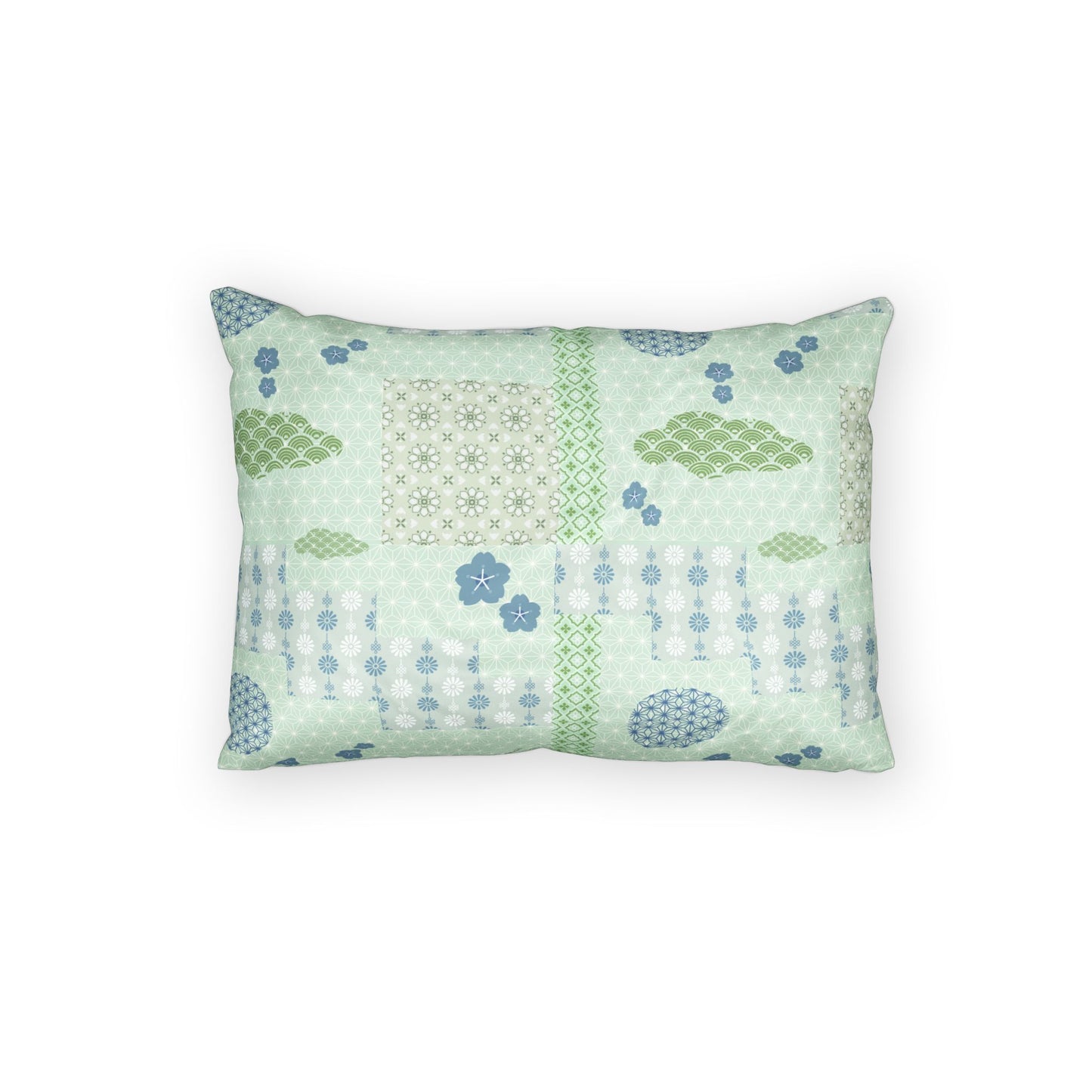 A rectangular decorative throw pillow featuring a patchwork-style print with light green, sage green, and blue patterns, including geometric grids, floral motifs, and dotted lines, set against a plain white background.