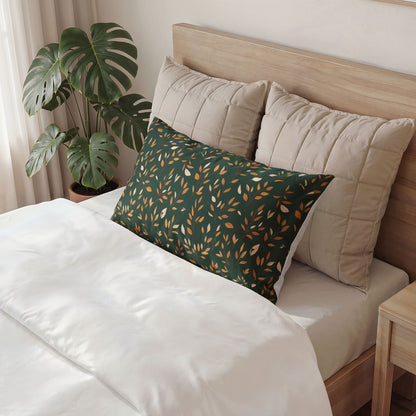 A dark green rectangular lumbar pillow with a gold leaf pattern rests on a bed with white bedding and beige pillows, next to a potted monstera plant.