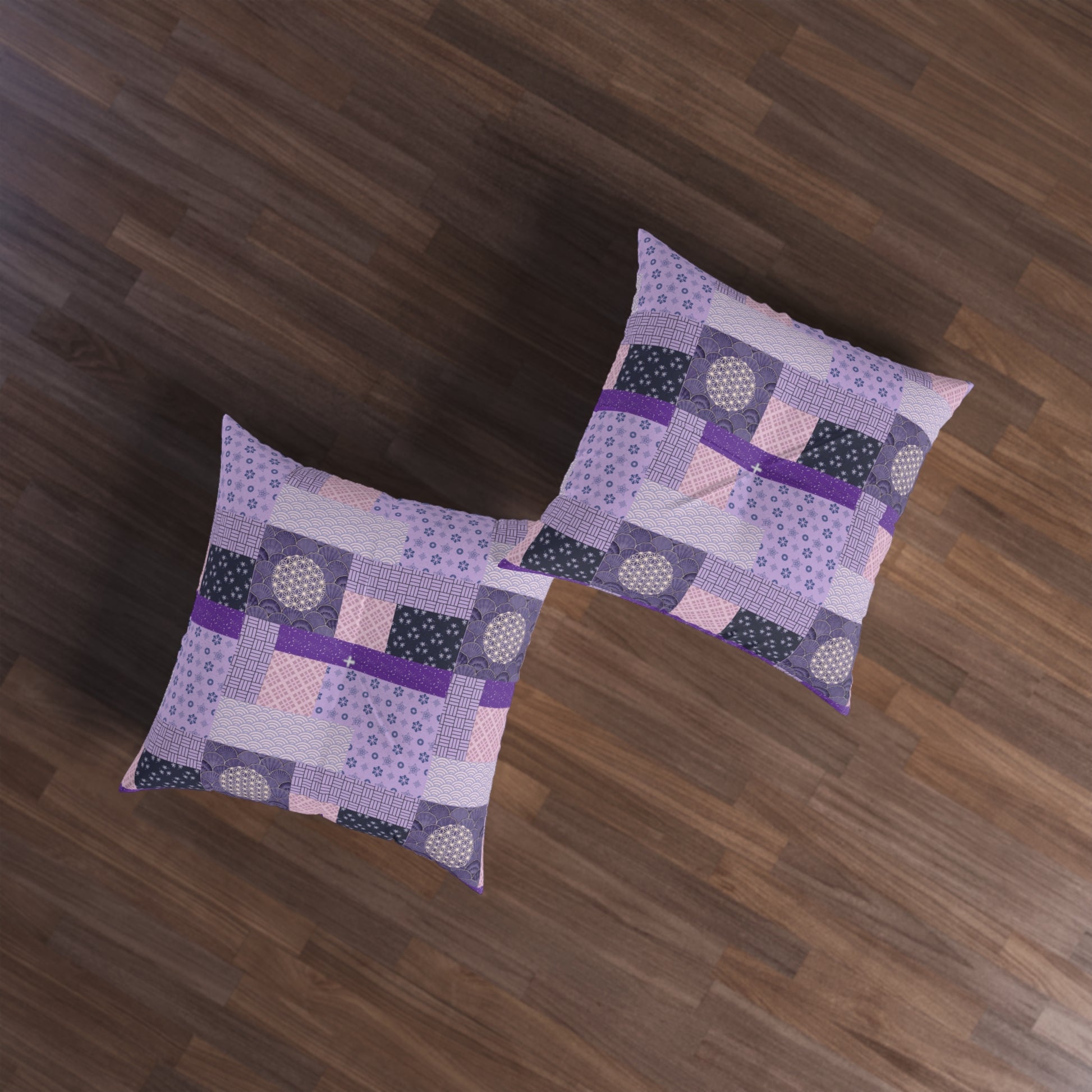 Two square throw pillows with a purple and pink patchwork quilt pattern, displayed on a dark brown wooden floor.