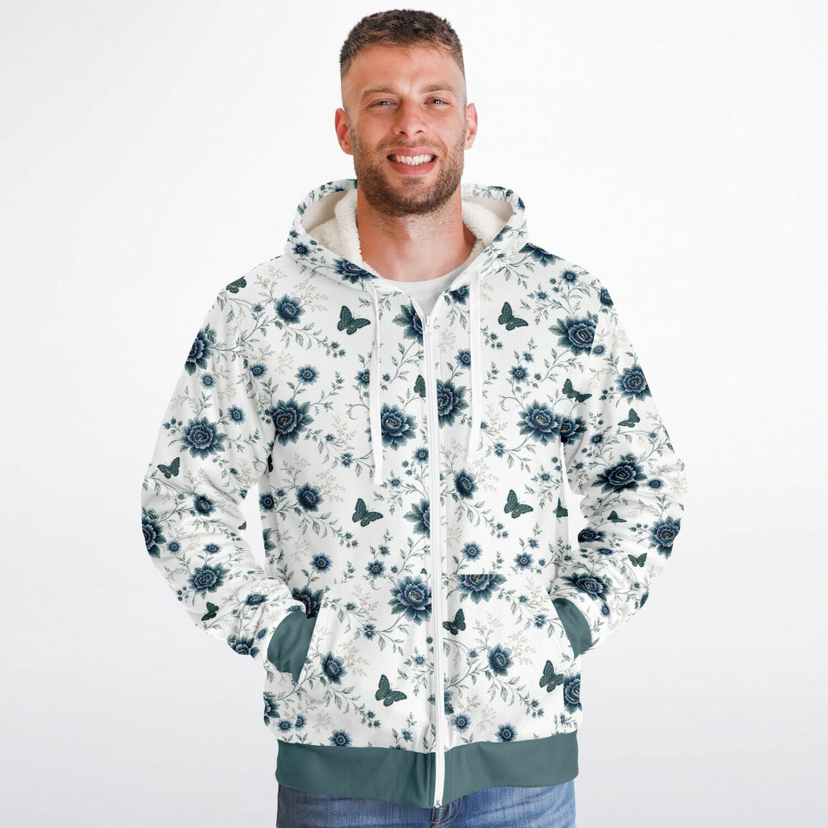 A man wearing a white zip-up hoodie with a dark blue floral and butterfly pattern, standing against a plain white background.