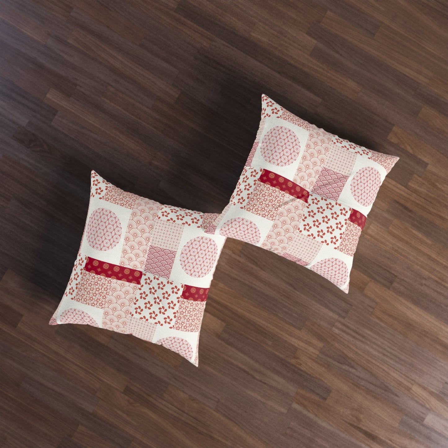 Two square throw pillows with a pink and red patchwork pattern on a cream background, displayed on a dark brown wooden floor.
