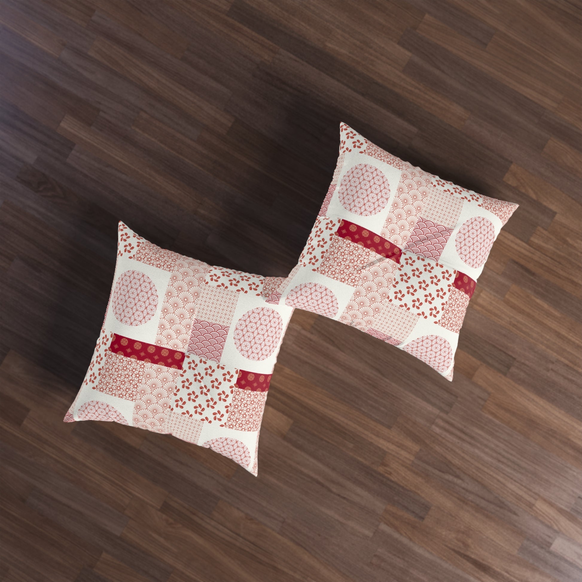 Two square throw pillows with a pink and red patchwork pattern on a cream background, displayed on a dark brown wooden floor.