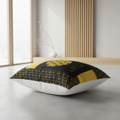 A square decorative floor pillow with a black and gold geometric pattern, styled in a minimalist modern room with a gray floor and light wood slats.