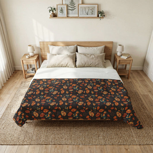 A neatly made bed in a bright, minimalist bedroom, featuring a dark charcoal comforter with an orange and brown autumn leaf pattern, styled with white and beige pillows and a woven jute rug.