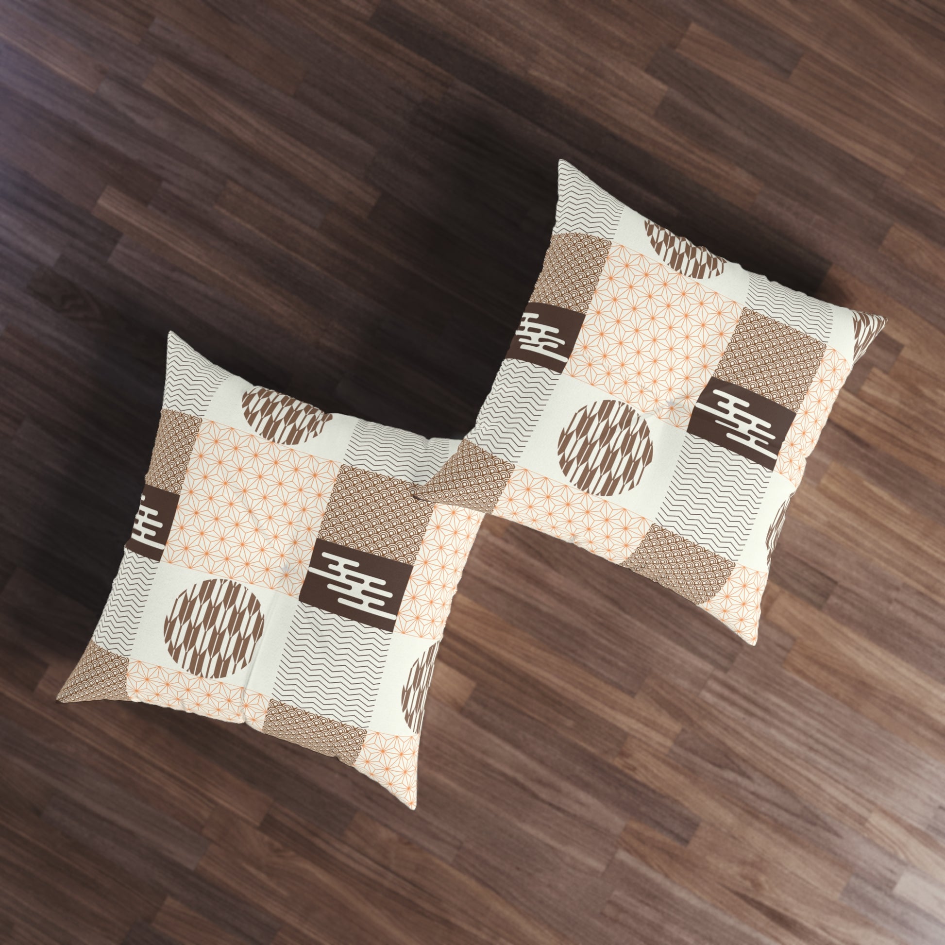 Two square throw pillows with a brown, beige, and white patchwork pattern featuring geometric and wavy motifs, displayed on a dark wood floor.