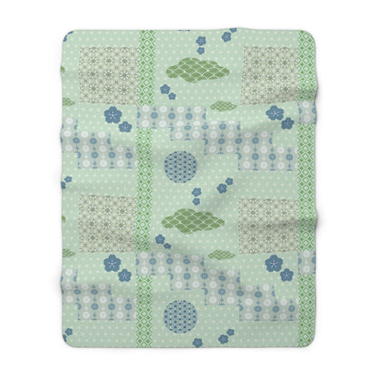 Patchwork blanket with geometric patterns on a light green background