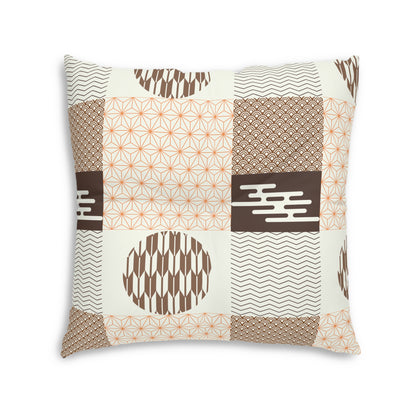 A square decorative throw pillow featuring a patchwork design of geometric and Japanese-inspired patterns in brown, beige, and orange on an off-white background.