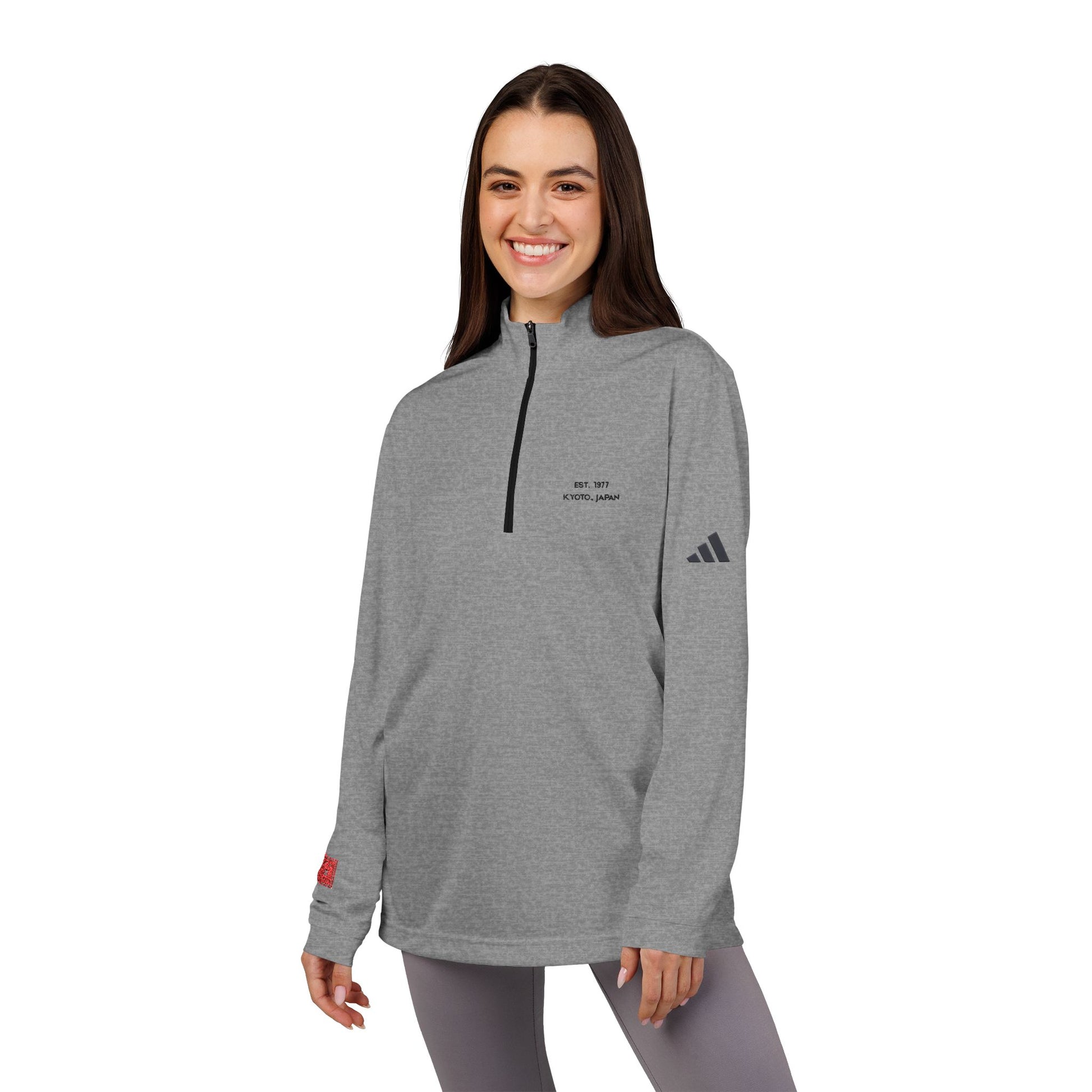 Woman wearing a gray Adidas pullover with a logo on a white background