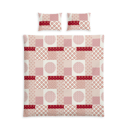 A bedding set featuring a patchwork quilt and two matching pillowcases with a geometric and floral patchwork pattern in shades of pink, red, and white.