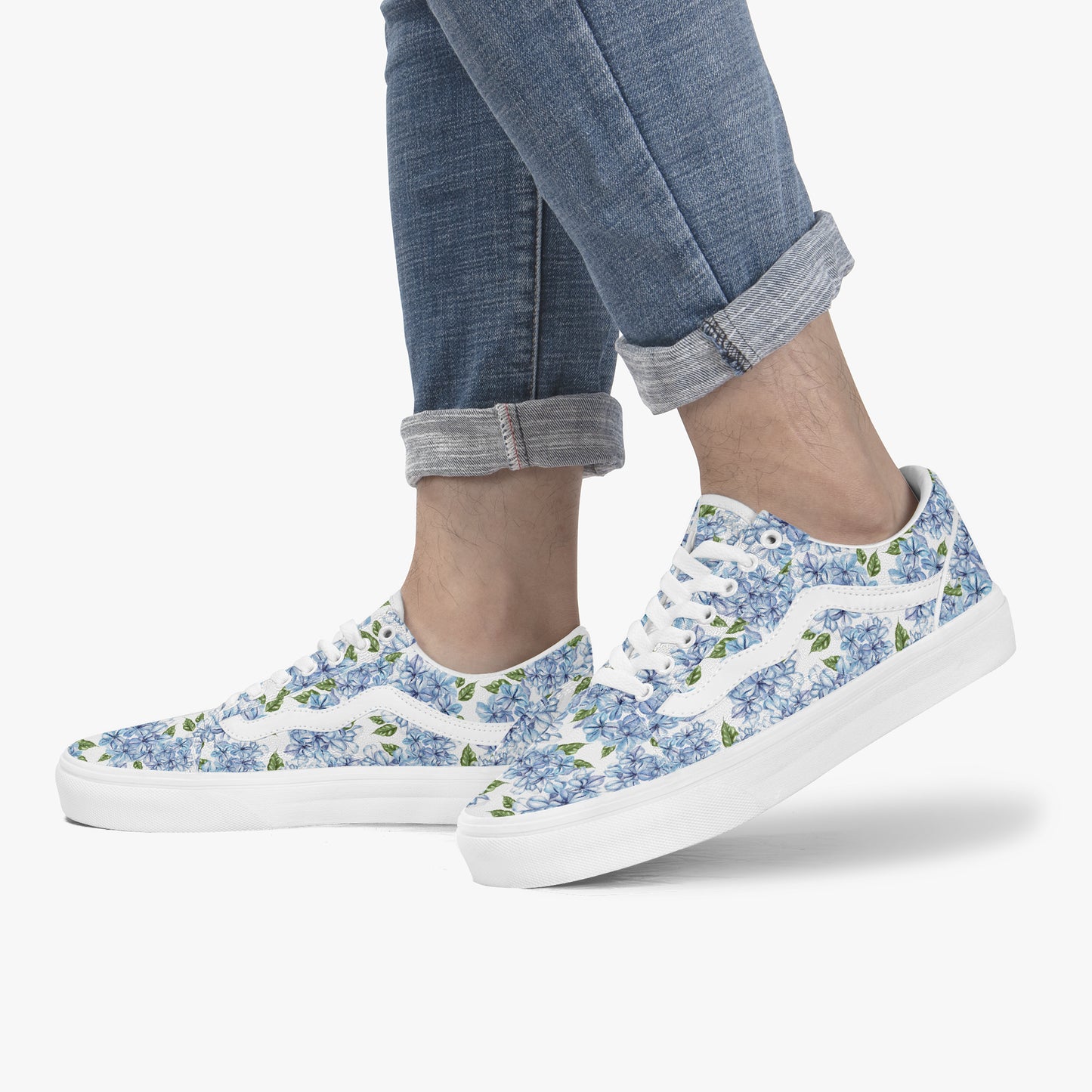 Blue floral sneakers worn with rolled-up jeans on a white background