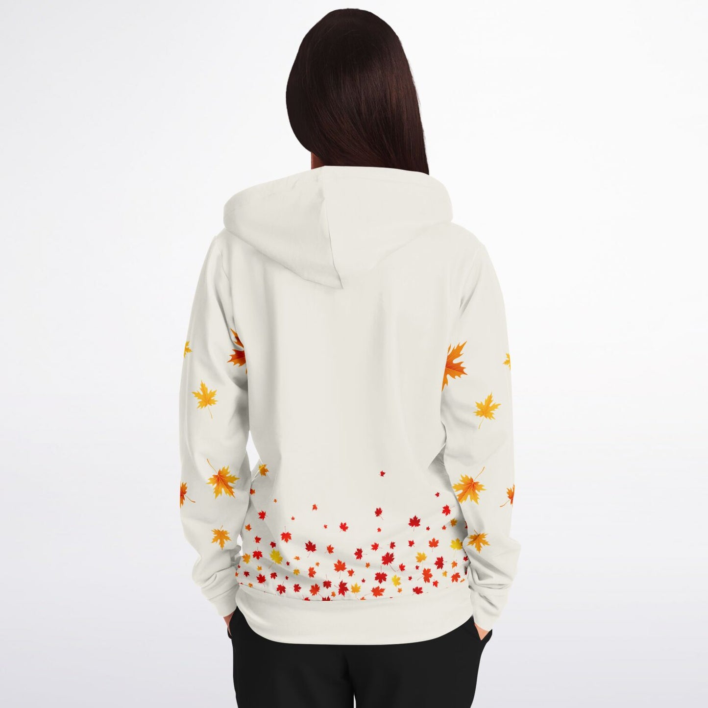 A woman viewed from behind wearing a white hoodie with a colorful autumn leaf pattern on the back and sleeves, paired with black pants, against a plain white background.