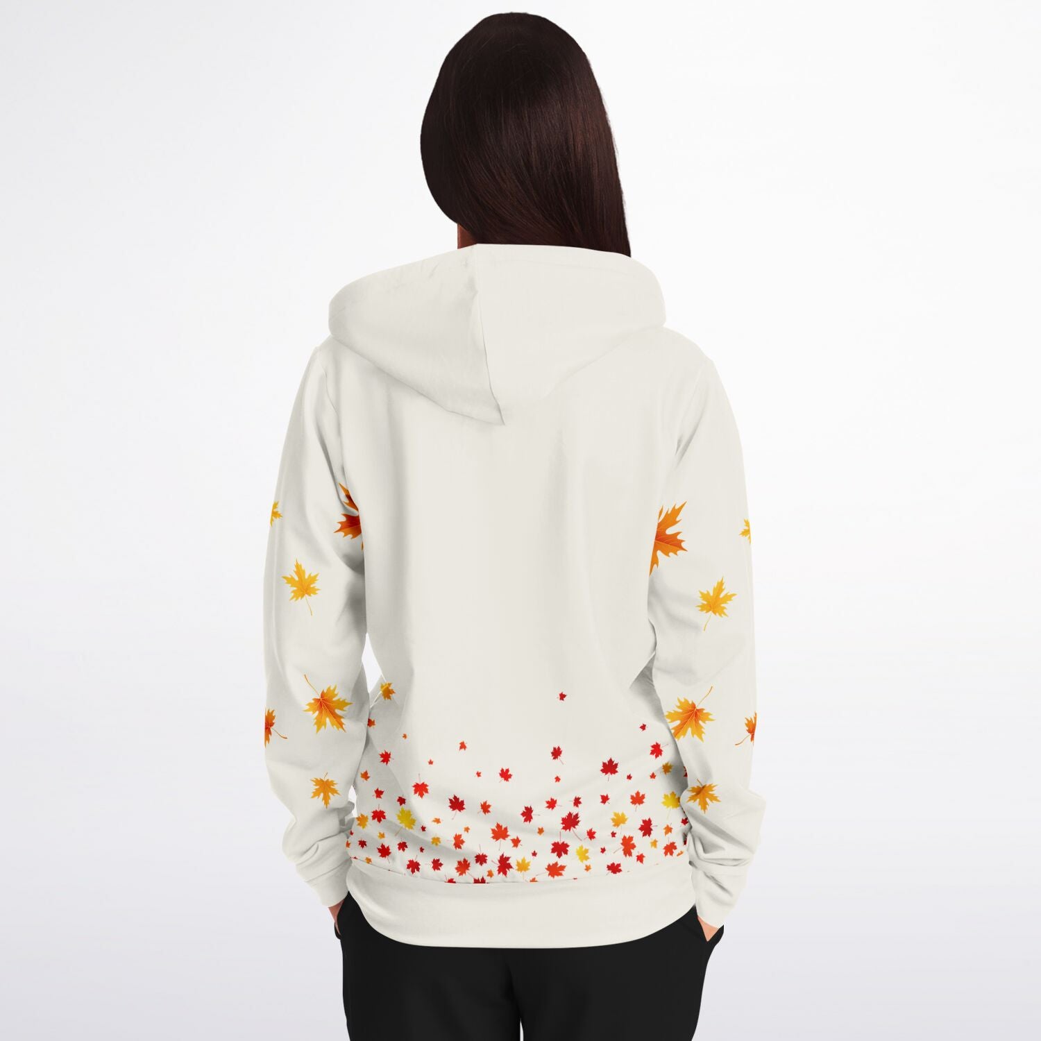 A woman viewed from behind wearing a white hoodie with a colorful autumn leaf pattern on the back and sleeves, paired with black pants, against a plain white background.
