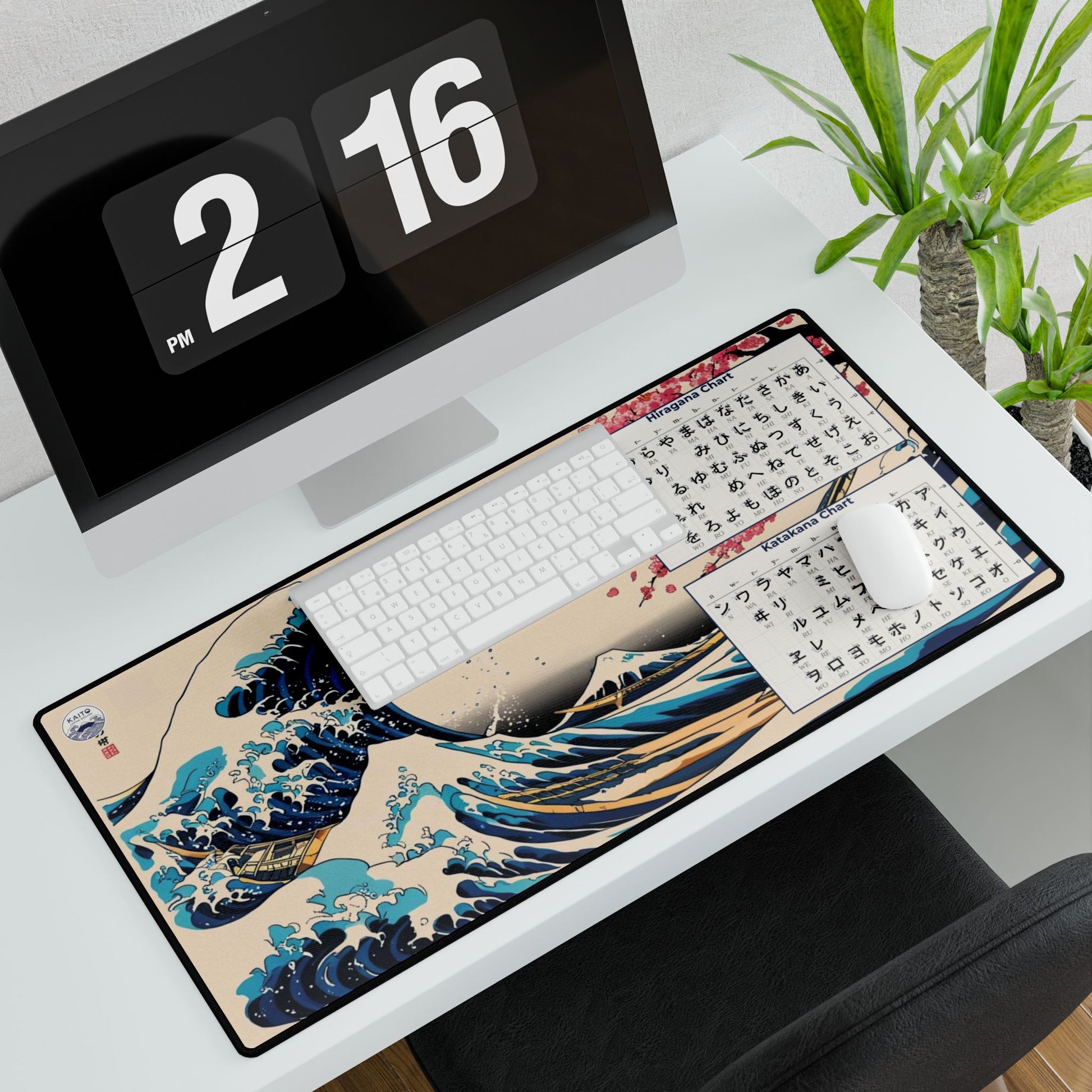 Desk setup with a large desk mat featuring a wave design, keyboard, and computer monitor.