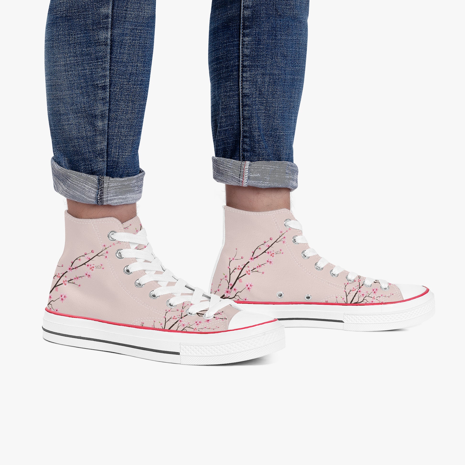 Pink high-top sneakers with floral design worn with rolled-up jeans on a white background