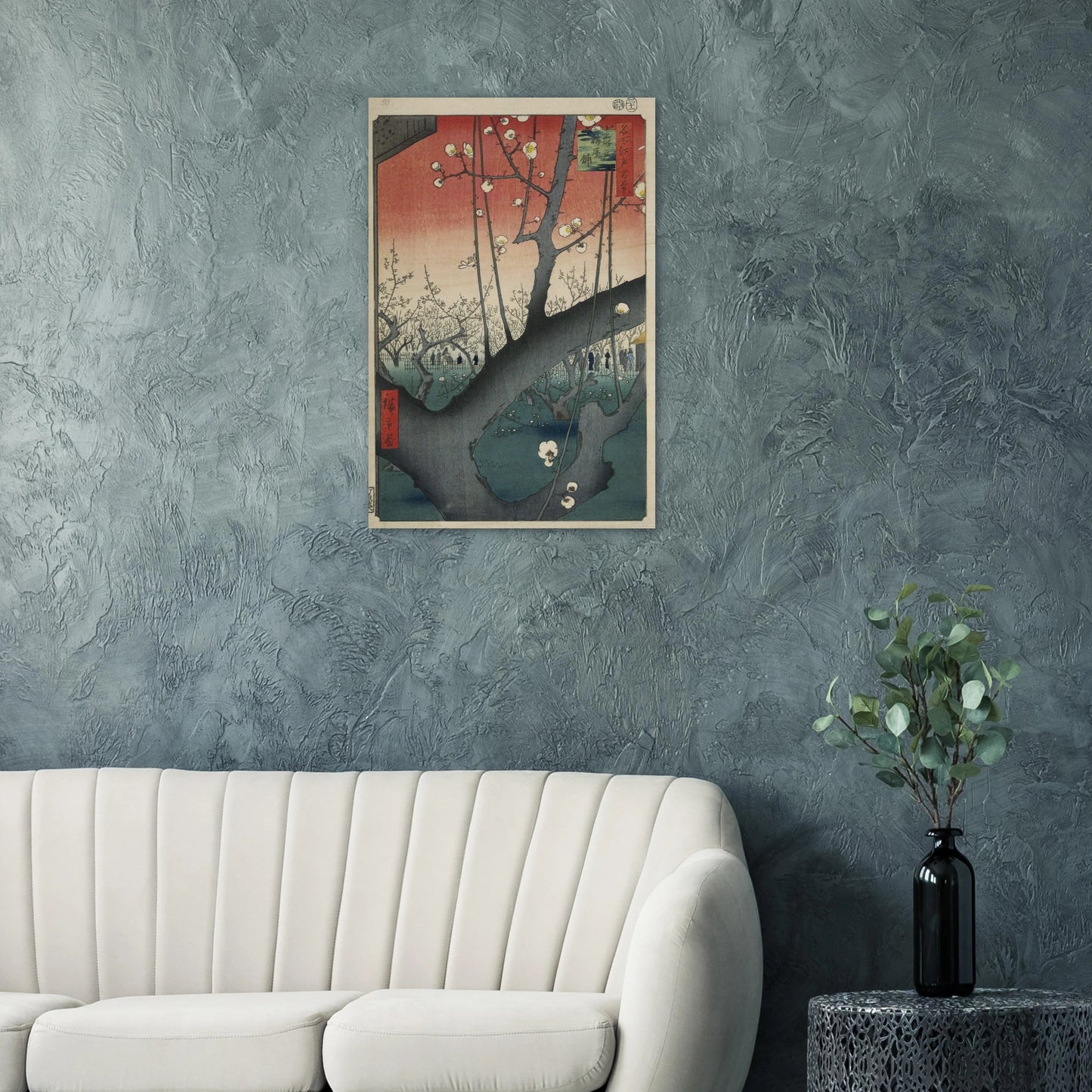 Framed artwork on a textured wall above a white sofa with a plant on a table.
