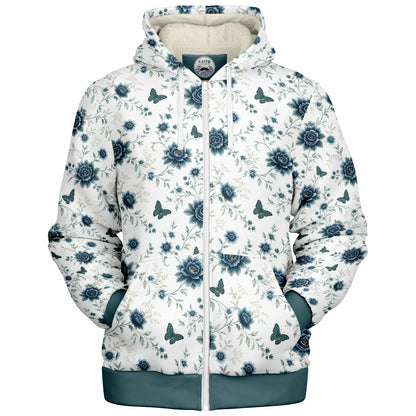 A white zip-up hoodie featuring a blue floral and butterfly pattern, with a solid teal hem and cuffs, and a cream-colored hood lining.
