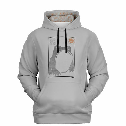 A light gray pullover hoodie with a black drawstring hood, featuring a central graphic print of a frog inside a rectangular frame with a small orange sun illustration in the upper right. The hoodie is displayed on a clean white background.