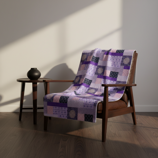 Wooden chair with a patchwork quilt draped over it in a room with a side table and vase.