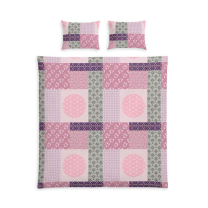 A patchwork quilt set featuring a duvet cover and two matching pillowcases in shades of pink, purple, and sage green, arranged on a plain white background.