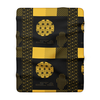Black blanket with gold geometric patterns on a white background