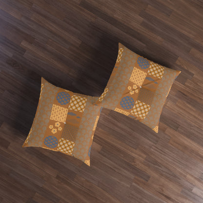Two square decorative throw pillows with a patchwork pattern in shades of brown, beige, and blue, arranged on a dark wood floor.