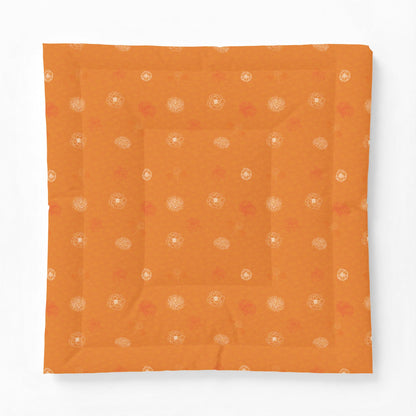 An orange square fabric item, likely a quilt or cushion cover, featuring a subtle pattern of small white and muted red floral motifs, displayed flat against a clean white background.